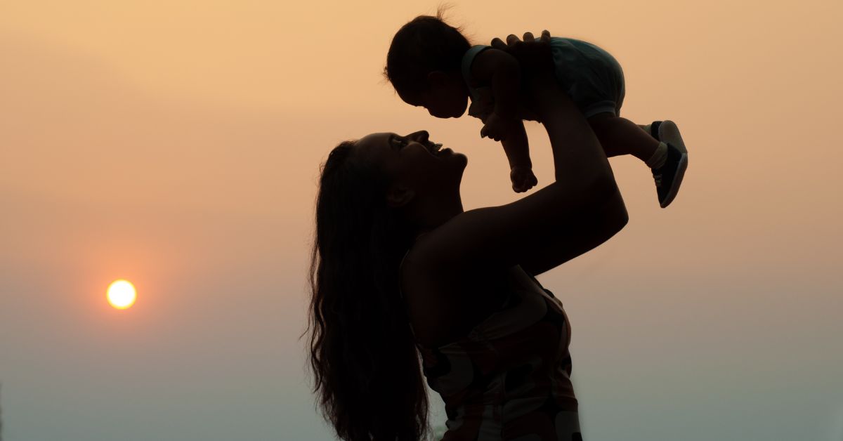 parent holding child sunset background